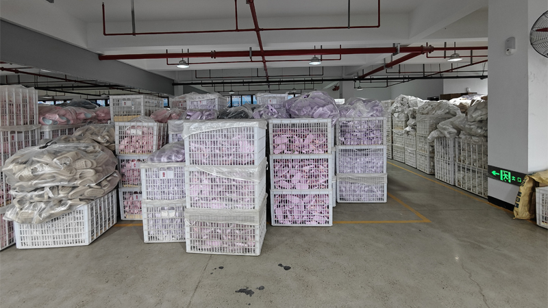 alt="Wholesale slipper factory storage area with finished EVA and PVC slippers packed in large baskets"